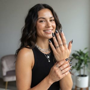 Colorful Star Black Press On Nails on a stylish American woman wearing black streetwear and silver jewelry with glossy almond-shaped celestial nail art